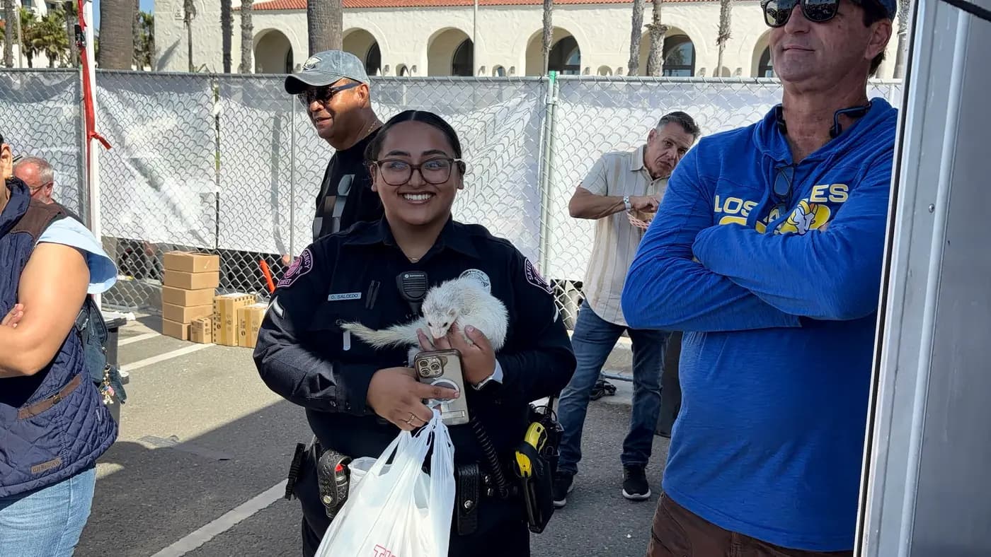 Smiling officer holding a ferret handed to her at a community event