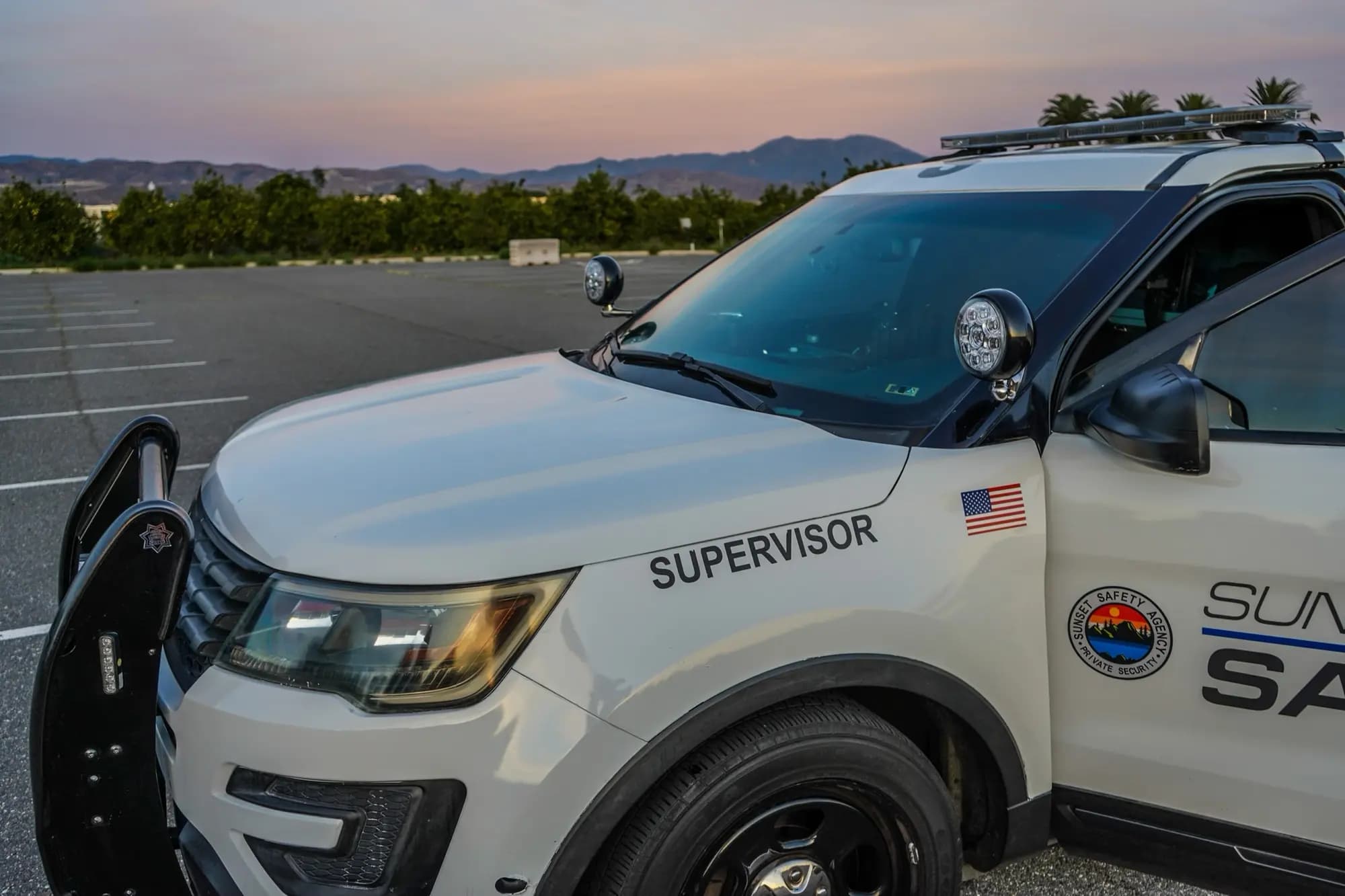 Patrol SUV hood at twilight with pink-purple sky over Orange County mountains