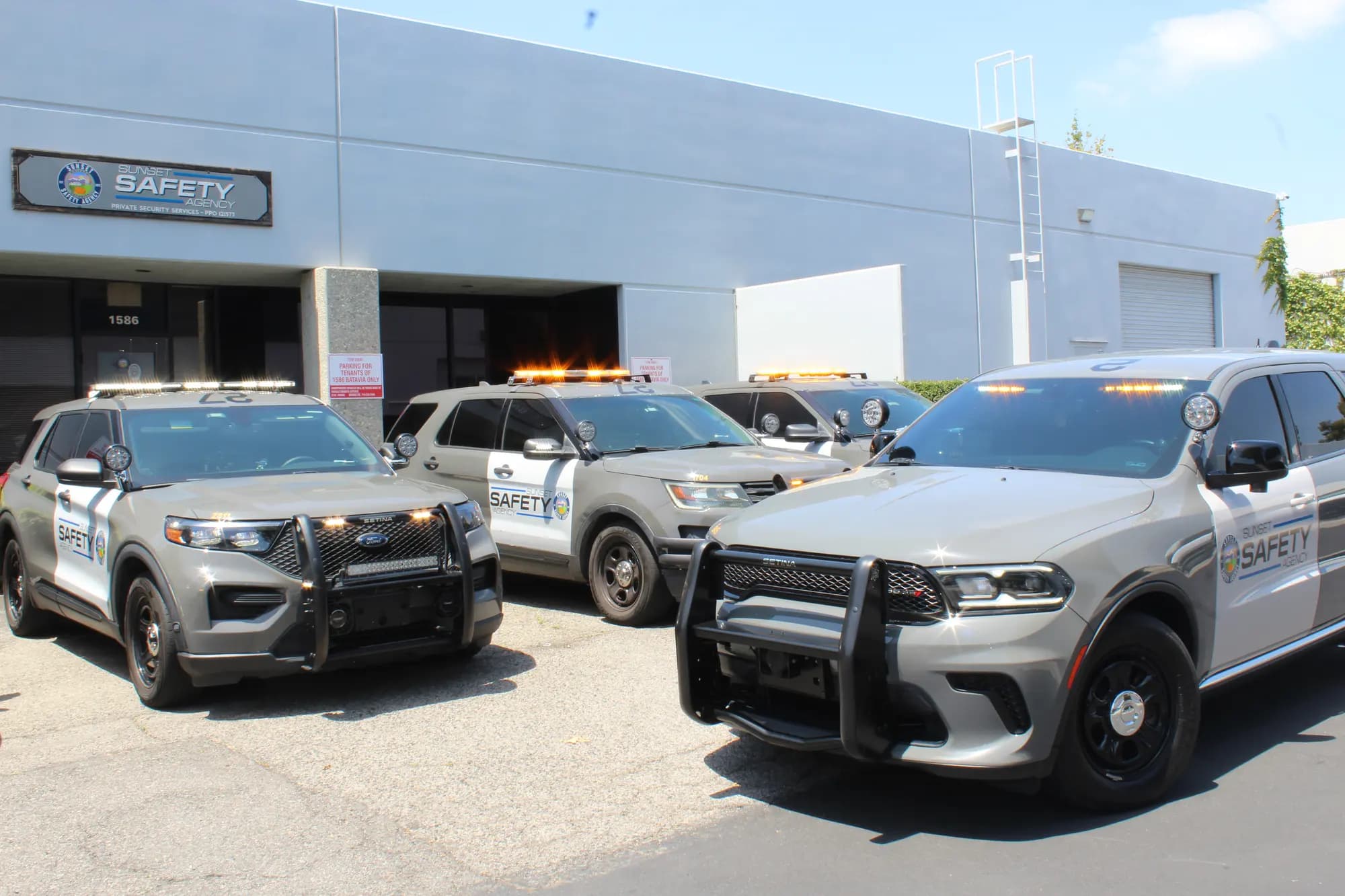 Dodge Durango patrol unit with lights lit posed beside Explorer units at headquarters
