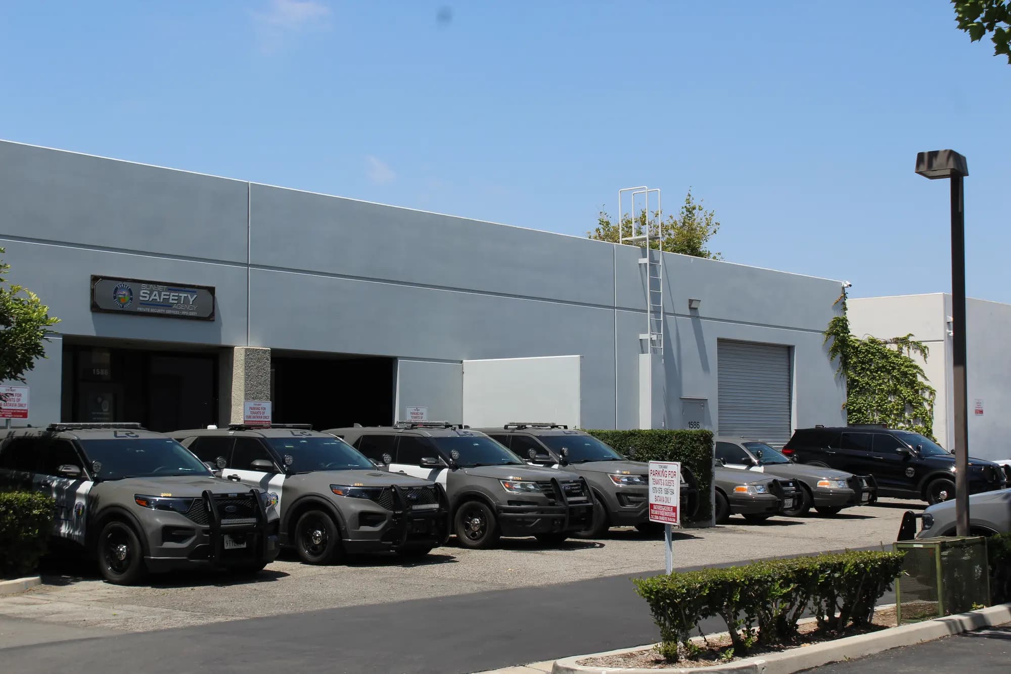 Wide view of the headquarters frontage with six fleet vehicles under blue sky