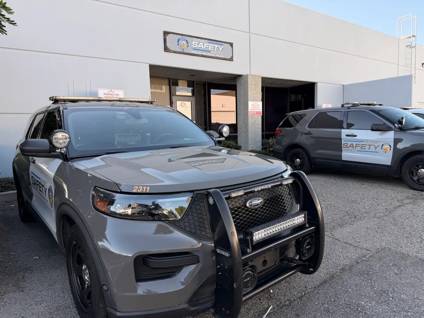 Two patrol Explorers parked in front of the Sunset Safety Agency headquarters sign