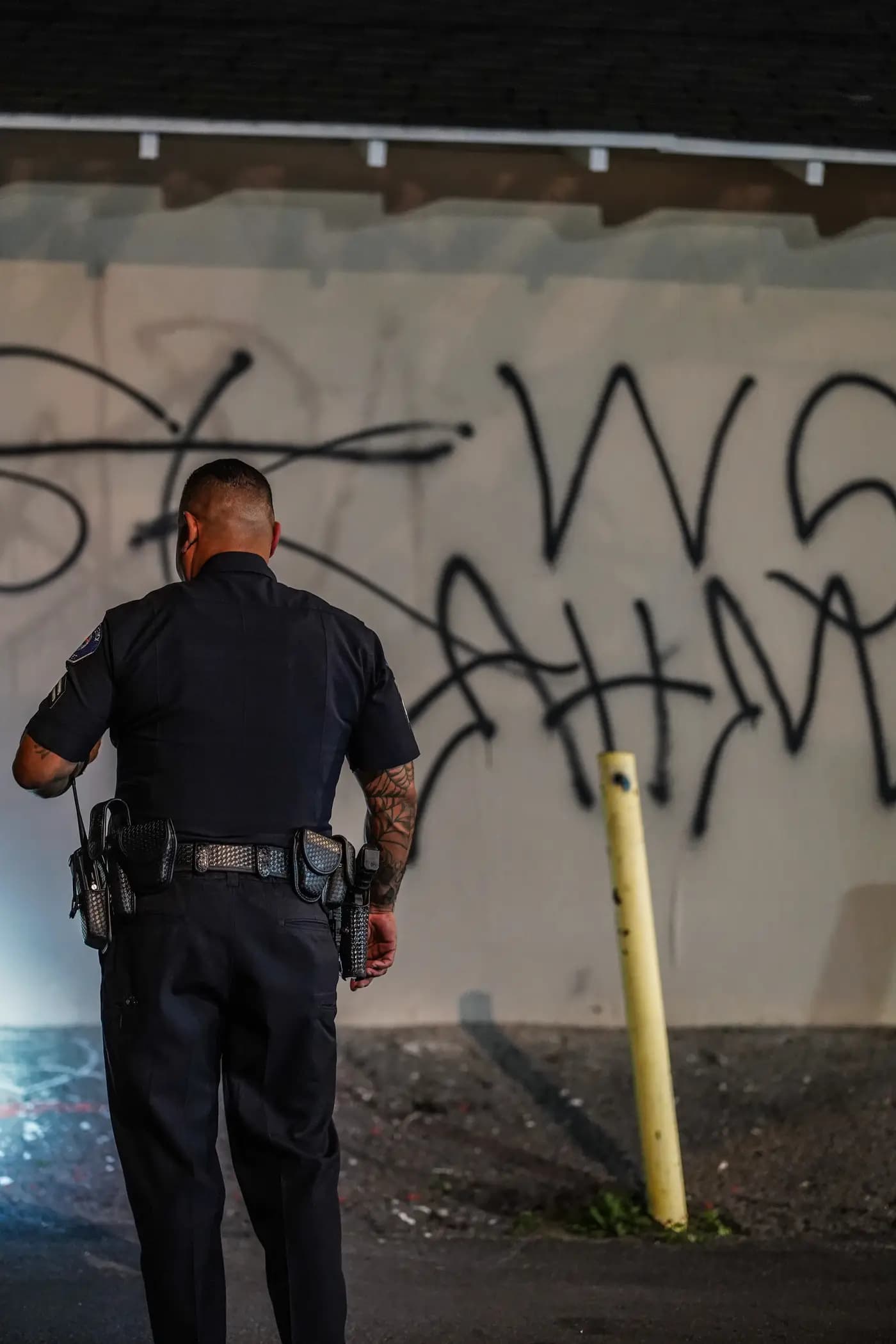 Officer keying his radio while documenting graffiti during a night patrol