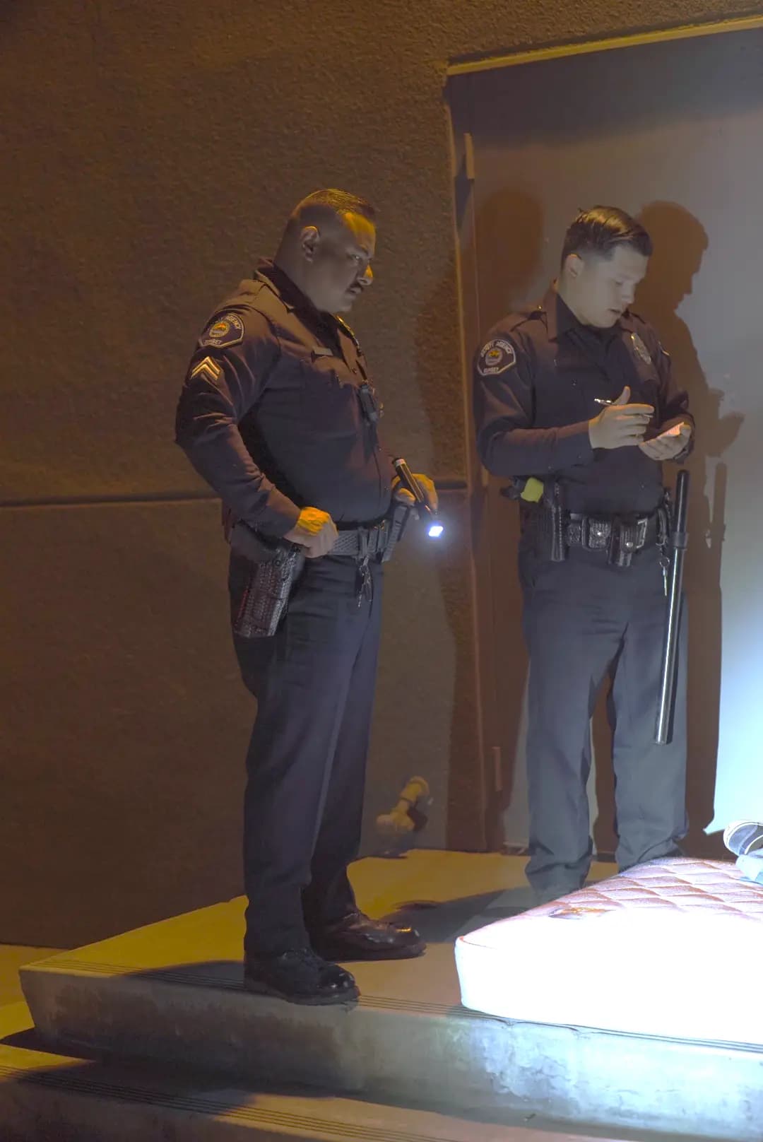 Two officers documenting illegally dumped items during a night patrol