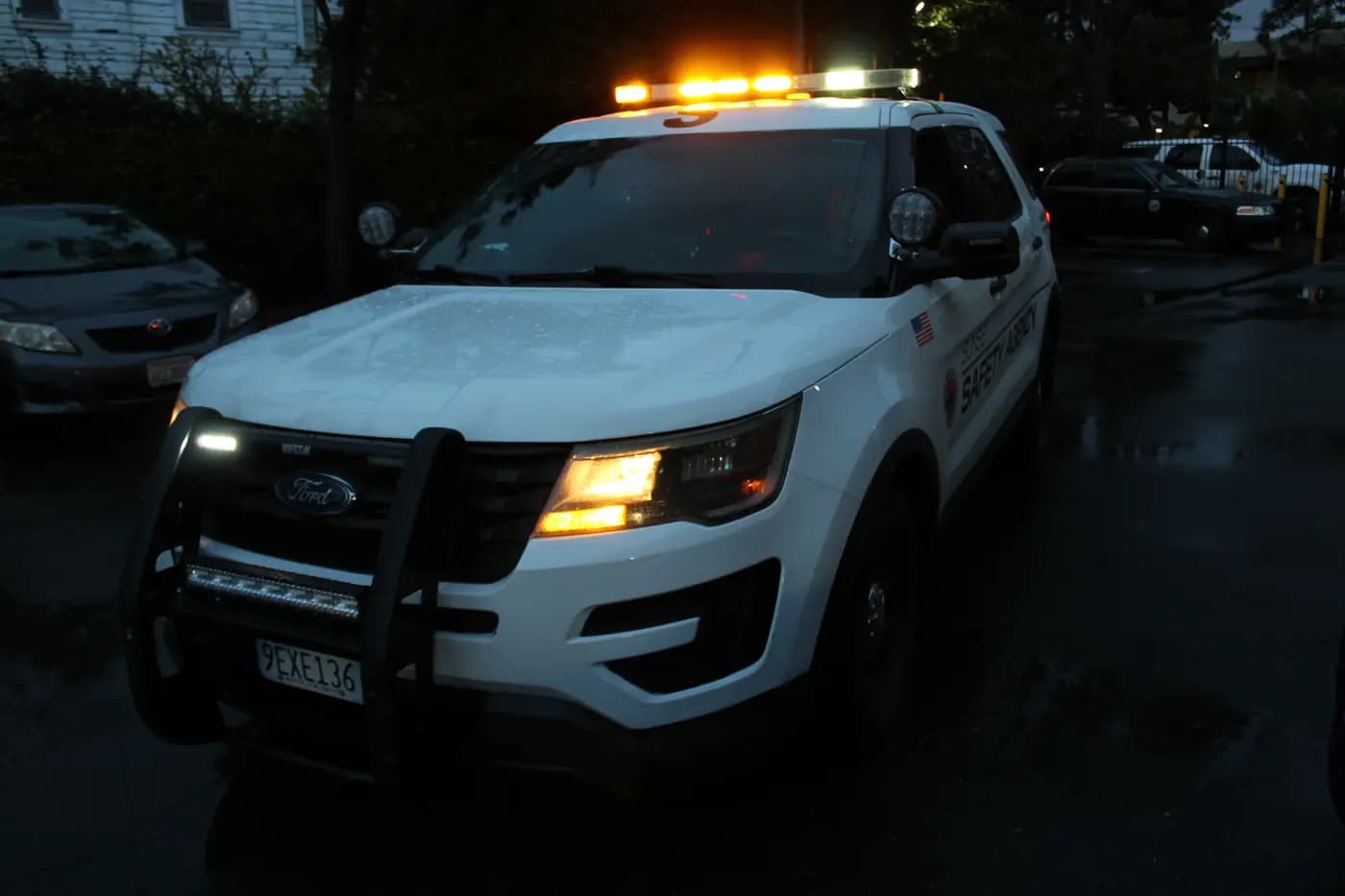 Patrol Explorer with amber lights on in a rainy apartment parking lot at dusk