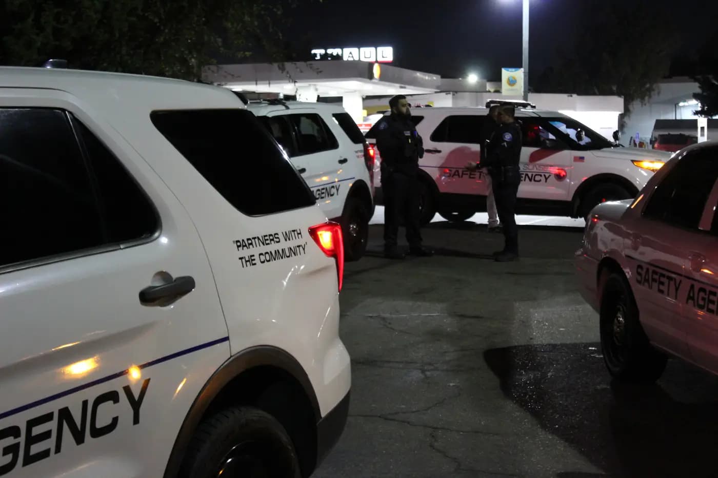 Officers talking between marked patrol units during a night shift briefing