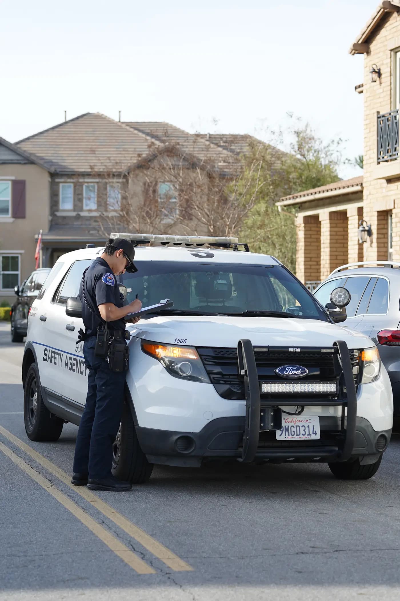 Officer writing a report on the hood of a patrol Explorer at an apartment community