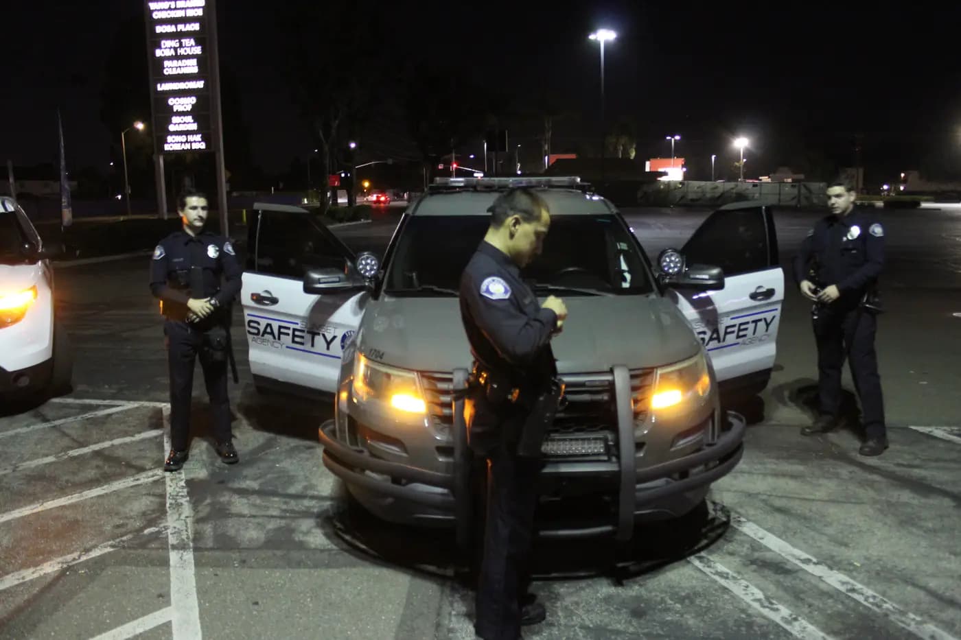 Officers in Class A uniforms by a patrol Explorer under ambient night light