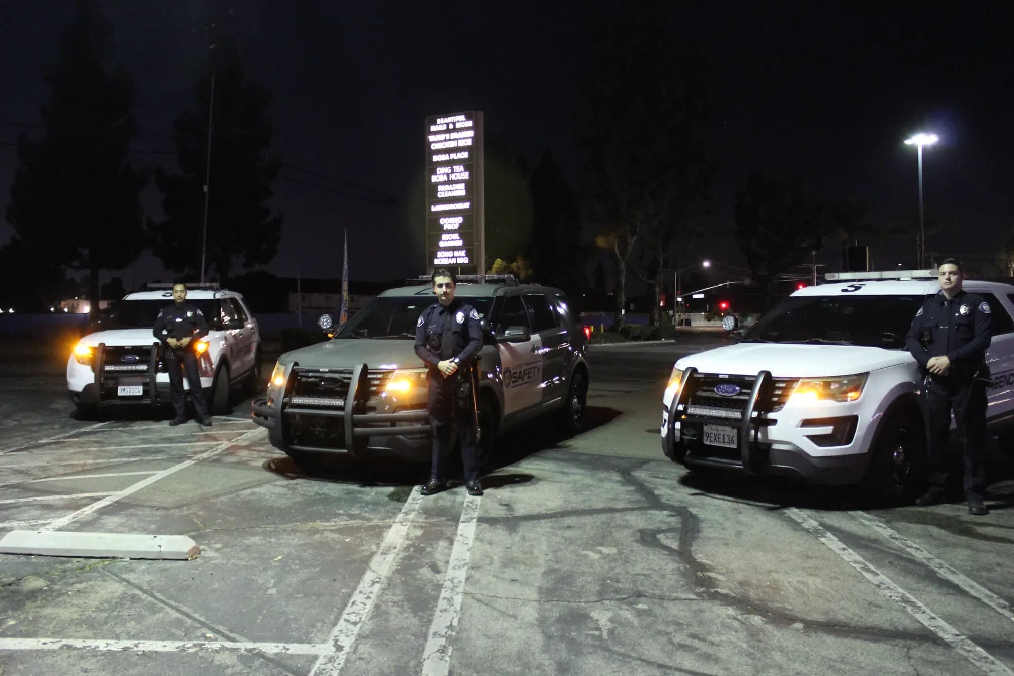 Three patrol Explorers side by side at night with an officer posted at each nose