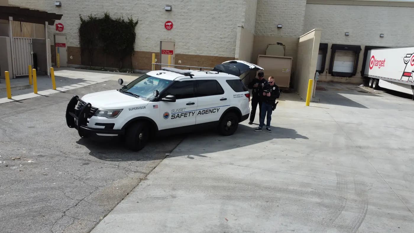 Low-altitude aerial of officers operating a drone beside a Supervisor patrol unit