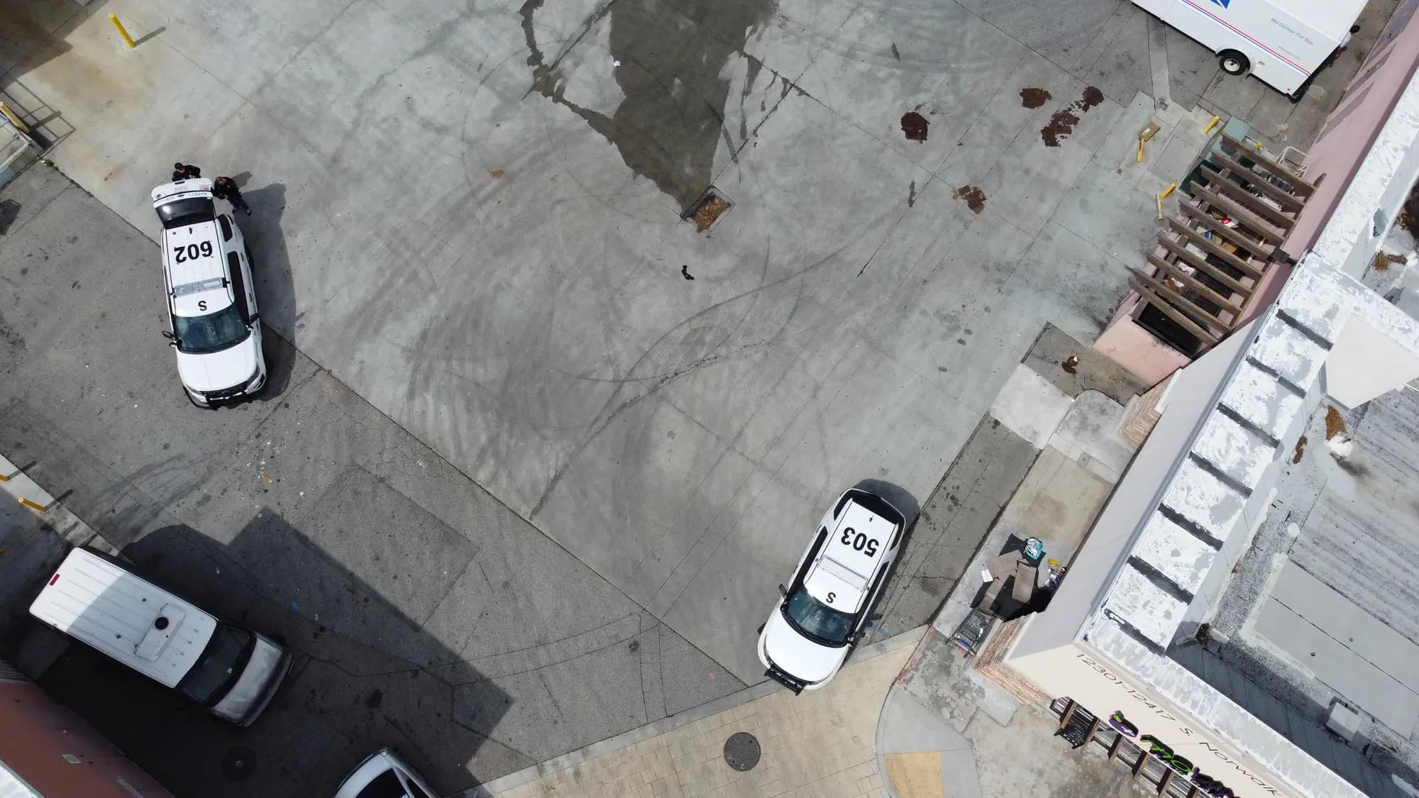 Straight-down aerial view of two marked patrol SUVs with officers standing beside them