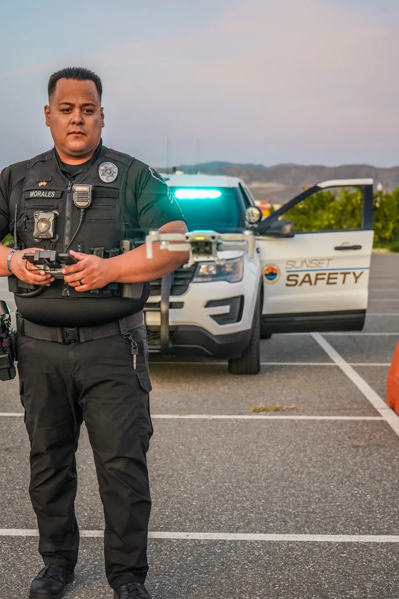 Sergeant piloting a quadcopter drone in front of a patrol Explorer at dusk
