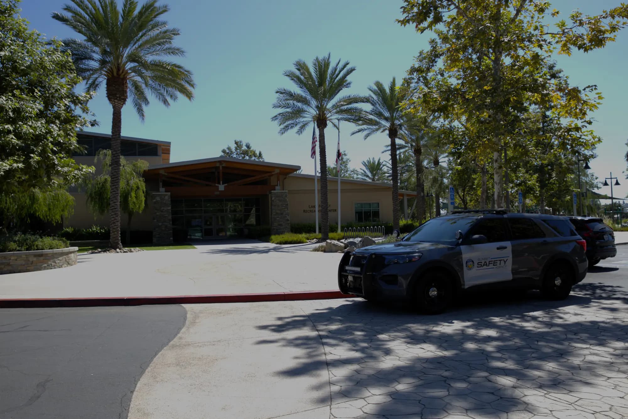 Patrol SUV parked at the curb of a recreation center with flags and palm trees