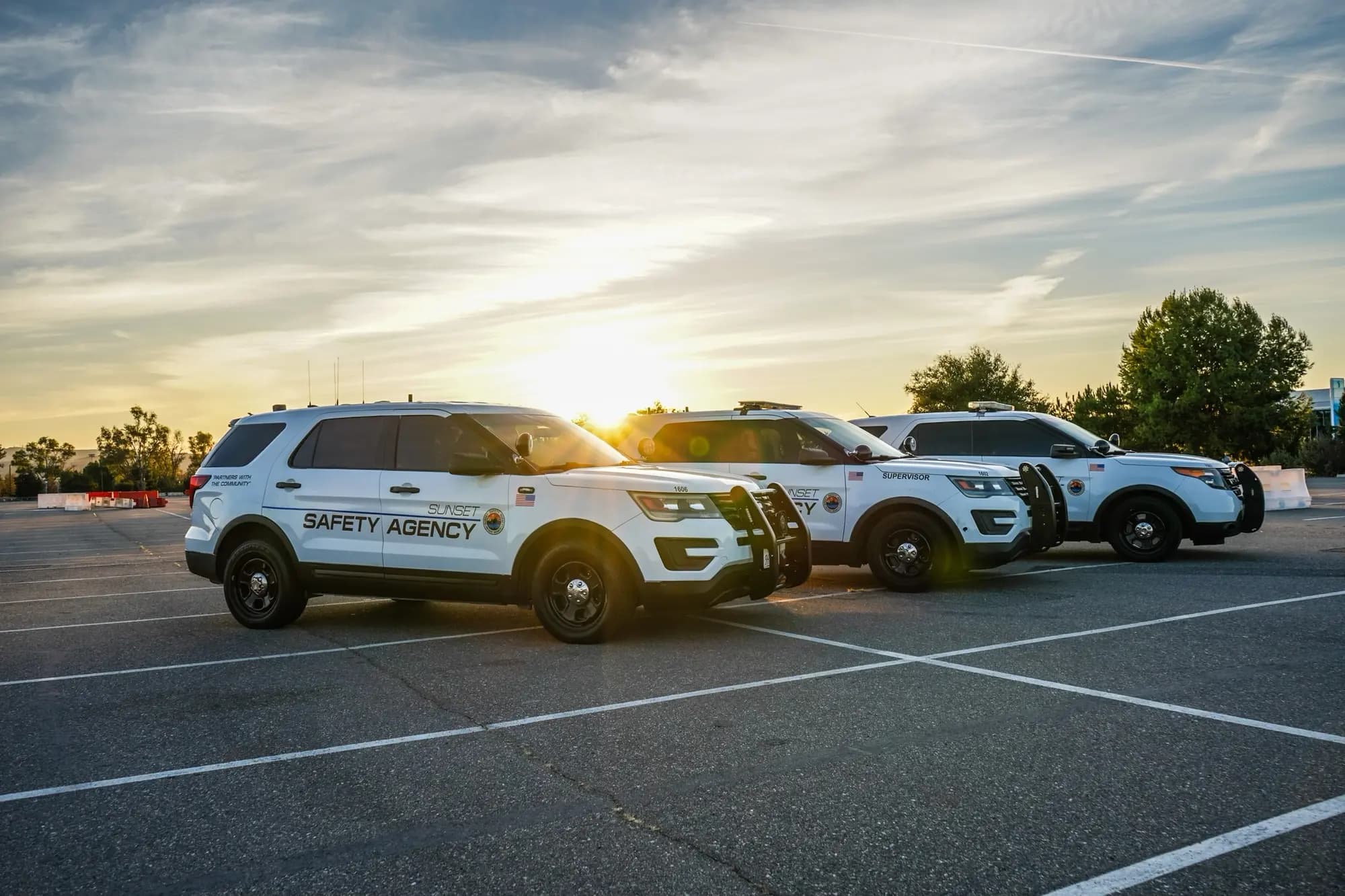 Three Sunset Safety patrol Explorers in a row with the setting sun flaring between them