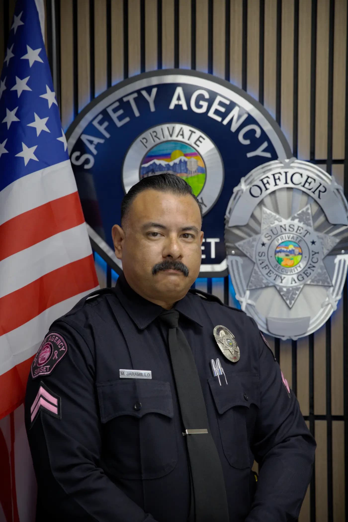 Studio roster portrait of a corporal in front of the agency shield wall